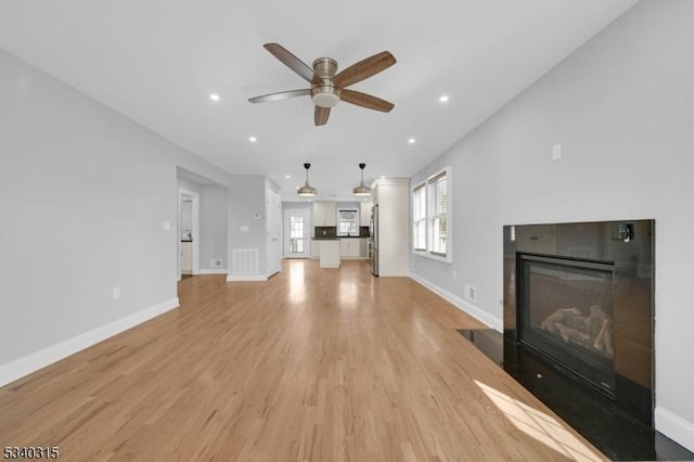 unfurnished living room featuring light wood-style floors, baseboards, visible vents, and a tiled fireplace