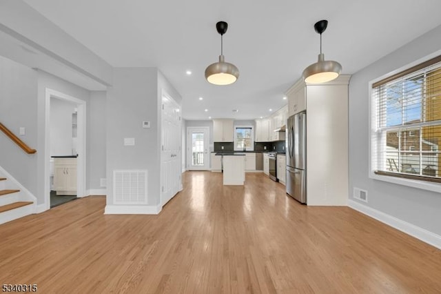 unfurnished living room featuring baseboards, visible vents, light wood finished floors, and stairs