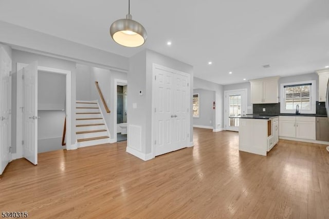 kitchen featuring pendant lighting, dark countertops, light wood-style flooring, and white cabinets