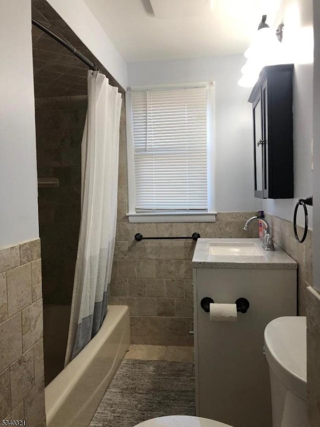 bathroom with toilet, a wainscoted wall, and tile walls