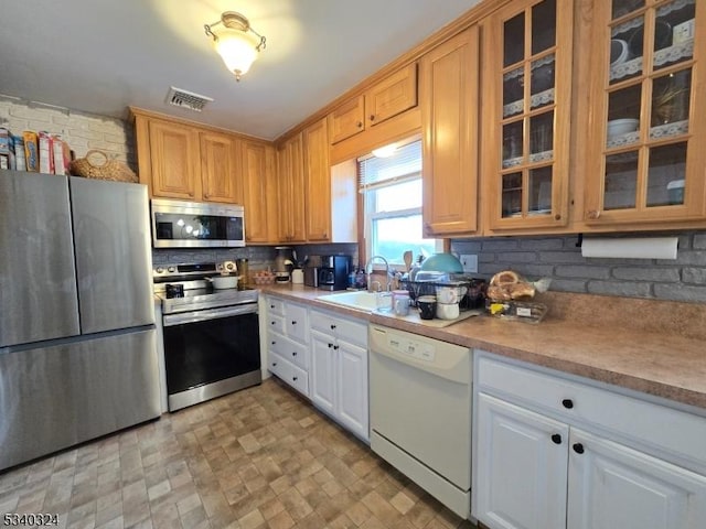 kitchen featuring appliances with stainless steel finishes, visible vents, a sink, and glass insert cabinets