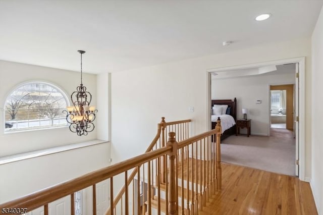 hallway featuring a notable chandelier, light wood finished floors, recessed lighting, an upstairs landing, and baseboards