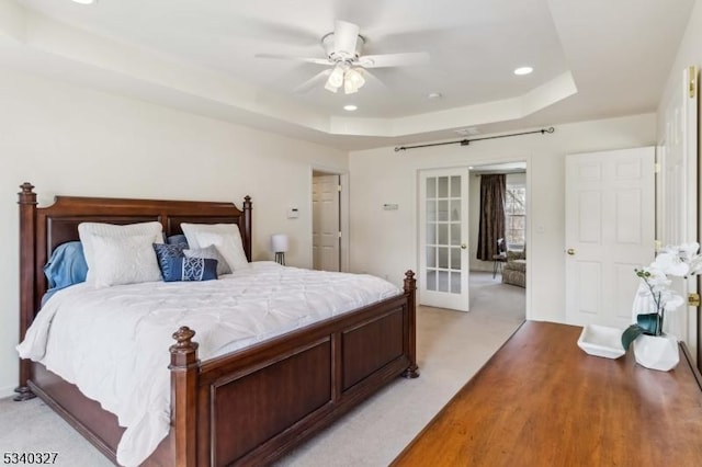 bedroom with light carpet, a tray ceiling, a ceiling fan, and recessed lighting