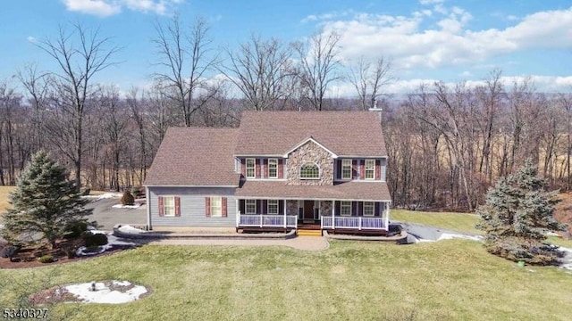 view of front of home with stone siding, a chimney, a front lawn, and a deck