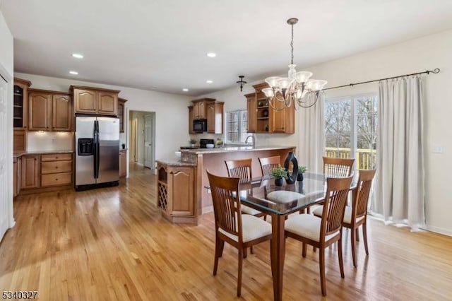 dining space featuring recessed lighting, light wood-style flooring, baseboards, and an inviting chandelier