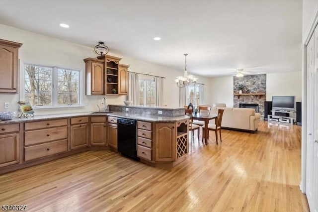 kitchen featuring black dishwasher, a peninsula, a stone fireplace, light wood-style floors, and open shelves