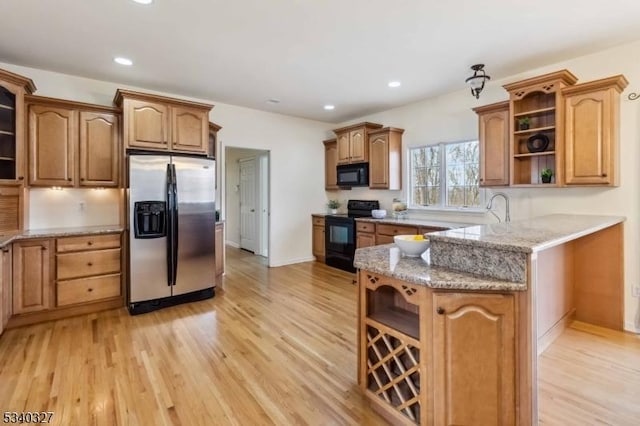 kitchen featuring light stone countertops, light wood finished floors, black appliances, and open shelves