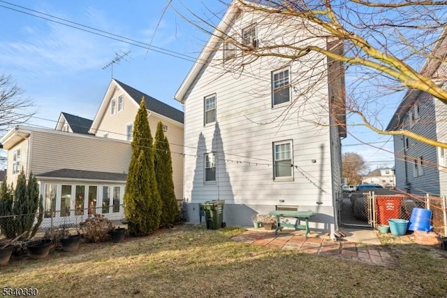 rear view of house featuring a patio, a lawn, fence, and a gate