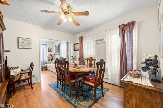 dining area featuring ceiling fan, a textured ceiling, light wood-type flooring, and baseboards