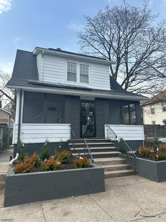 view of front of property with a sunroom and roof with shingles