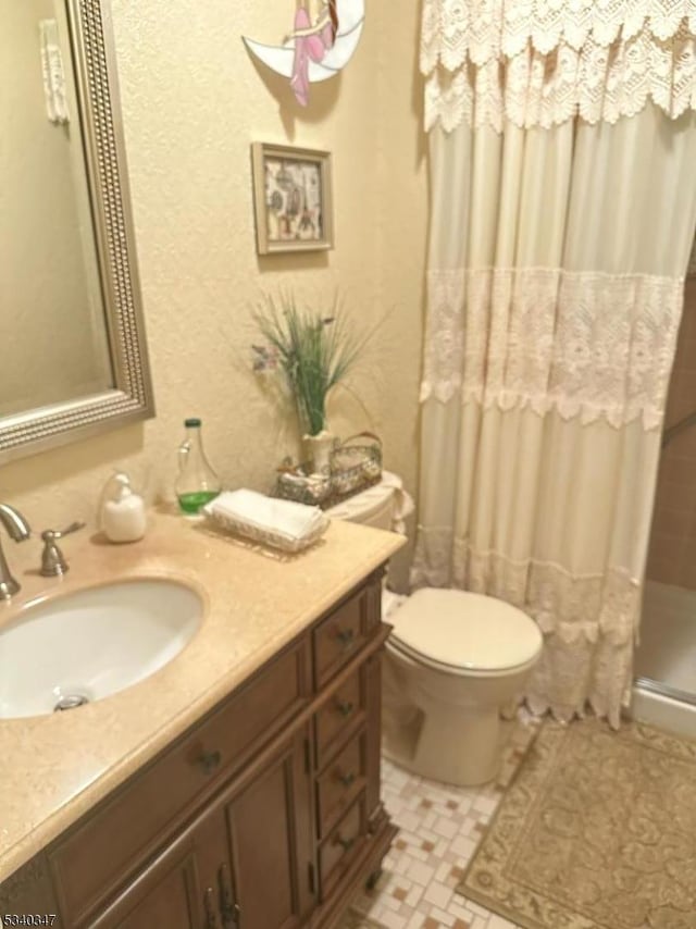 bathroom featuring toilet, a stall shower, and vanity