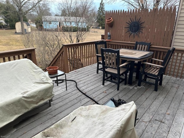 deck with a storage shed, outdoor dining space, and an outdoor structure