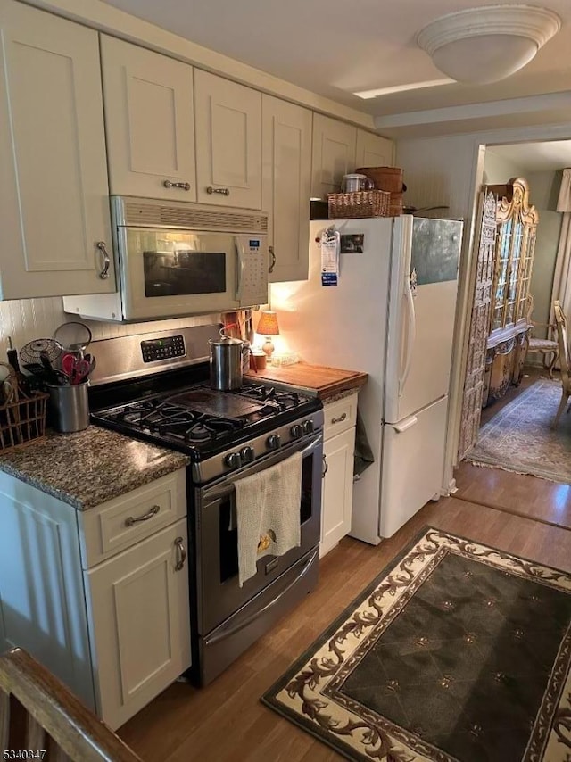 kitchen featuring white appliances, white cabinetry, and dark wood finished floors