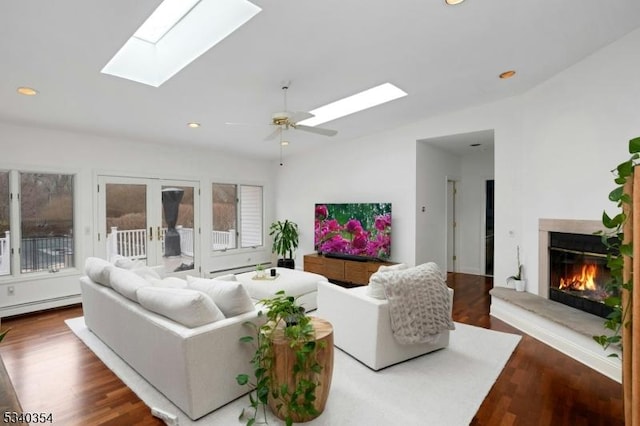 living room featuring a baseboard heating unit, a fireplace, wood finished floors, french doors, and lofted ceiling with skylight