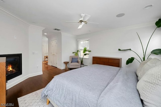 bedroom with ornamental molding, a glass covered fireplace, visible vents, and wood finished floors