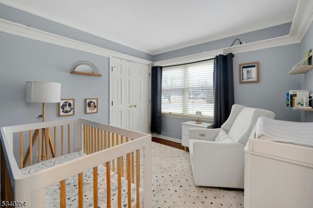 bedroom with ornamental molding, a closet, a crib, and baseboards