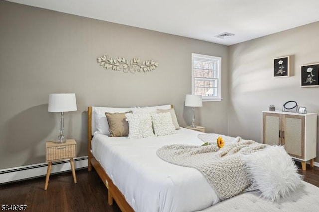 bedroom with a baseboard heating unit, wood finished floors, and visible vents