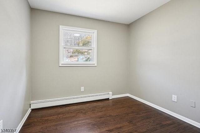 spare room featuring dark wood-style floors, baseboards, and a baseboard heating unit