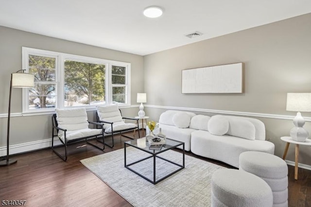 living room featuring baseboards, visible vents, and wood finished floors