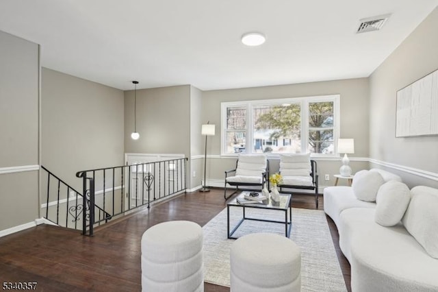 living area featuring baseboards, visible vents, and wood finished floors