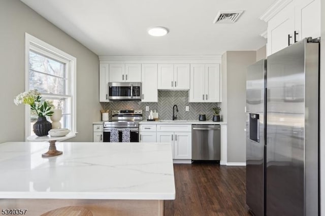 kitchen featuring appliances with stainless steel finishes, visible vents, a sink, and white cabinetry