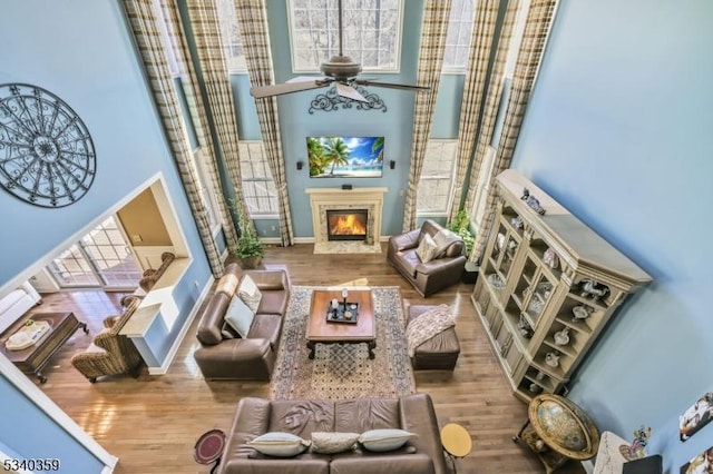 interior space featuring ceiling fan, a premium fireplace, a high ceiling, and wood finished floors