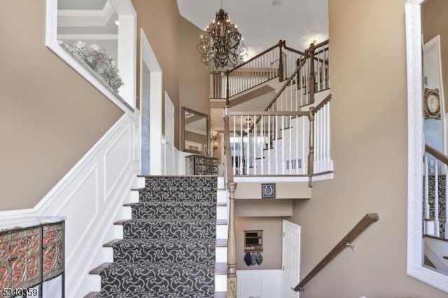 stairs with an inviting chandelier and a towering ceiling