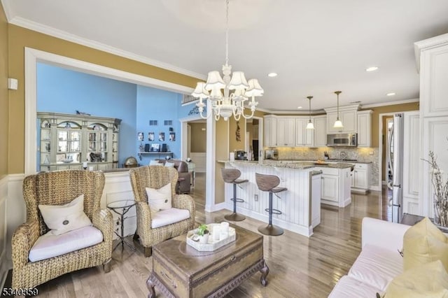 living room featuring an inviting chandelier, crown molding, recessed lighting, and light wood finished floors