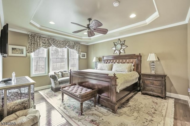 bedroom featuring a raised ceiling, wood finished floors, baseboards, and ornamental molding