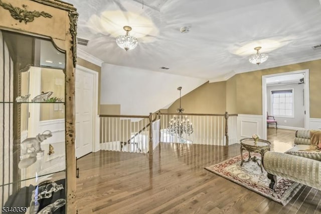 interior space with wood finished floors, a chandelier, wainscoting, and ornamental molding