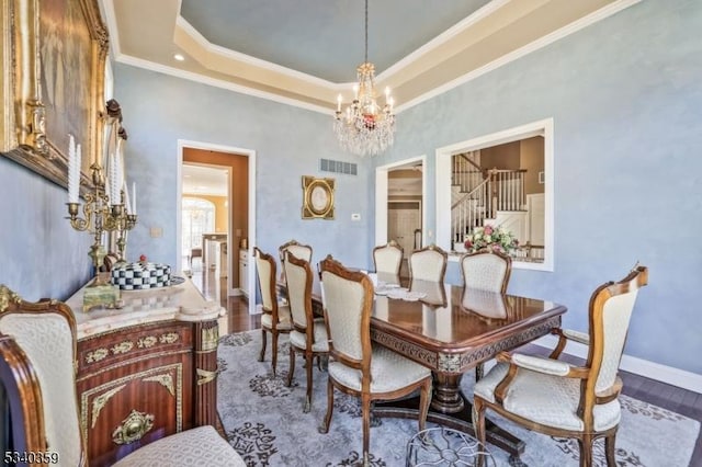 dining room featuring visible vents, crown molding, an inviting chandelier, wood finished floors, and a raised ceiling