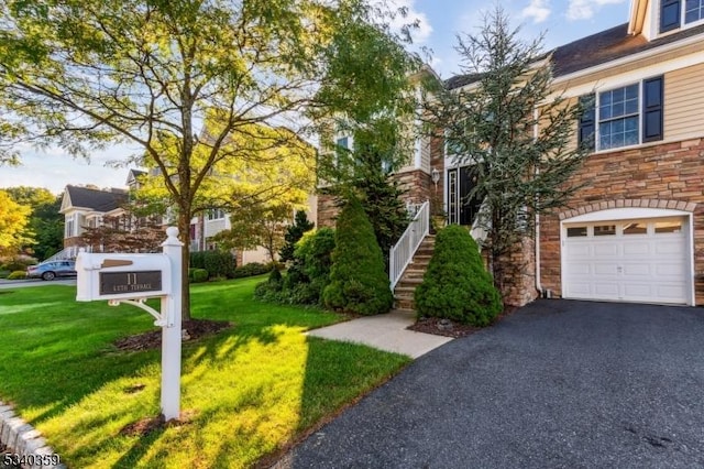 exterior space featuring aphalt driveway, stairway, a yard, and an attached garage