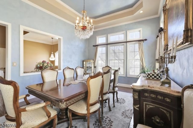 dining room featuring a raised ceiling, dark wood-type flooring, an inviting chandelier, and ornamental molding