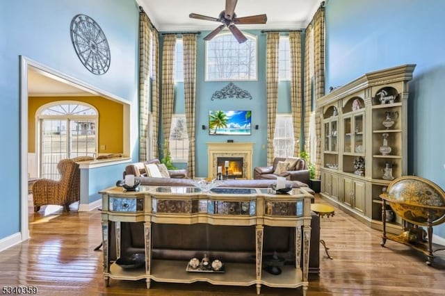 sitting room with a high ceiling, a lit fireplace, and wood finished floors