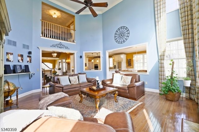 living room with stairs, visible vents, and hardwood / wood-style floors