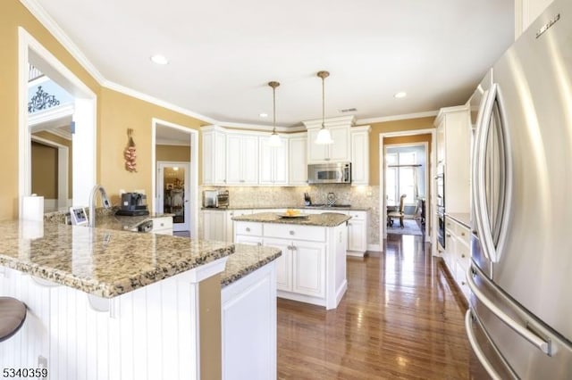 kitchen with a peninsula, a sink, decorative backsplash, dark wood-type flooring, and appliances with stainless steel finishes