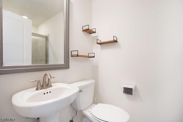 bathroom with toilet, a shower stall, and a sink