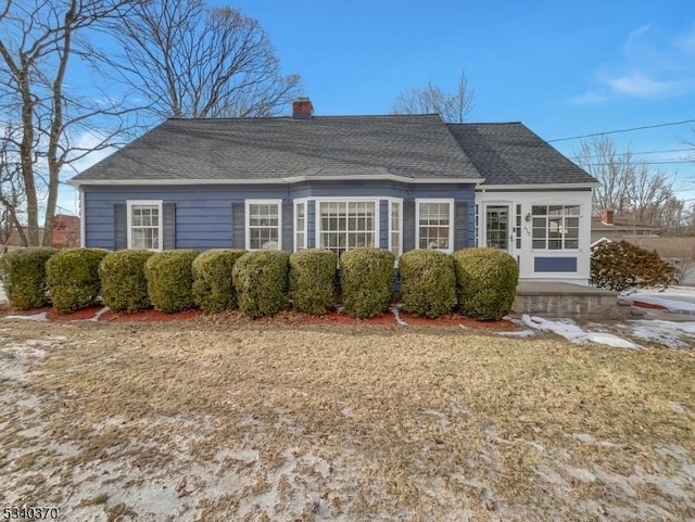 rear view of house featuring a shingled roof and a chimney