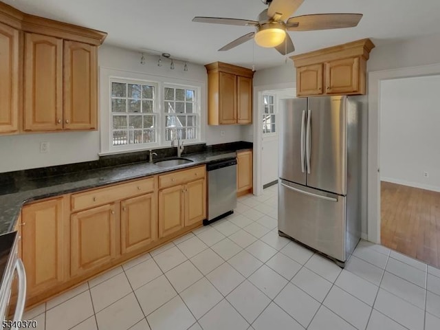 kitchen with light tile patterned floors, ceiling fan, a sink, appliances with stainless steel finishes, and dark countertops