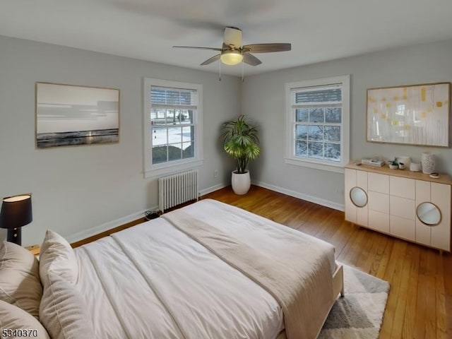 bedroom featuring radiator, a ceiling fan, baseboards, and hardwood / wood-style floors