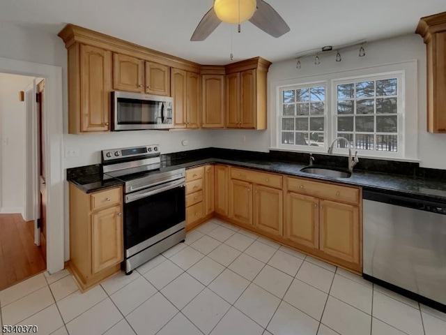 kitchen with dark countertops, ceiling fan, appliances with stainless steel finishes, and a sink