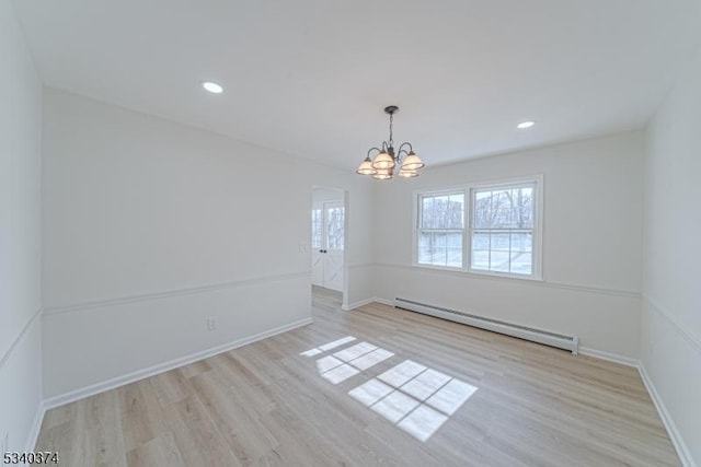 spare room with a baseboard heating unit, a chandelier, light wood-style flooring, and baseboards