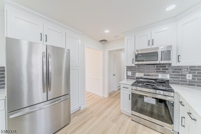 kitchen with light stone counters, stainless steel appliances, visible vents, white cabinets, and tasteful backsplash