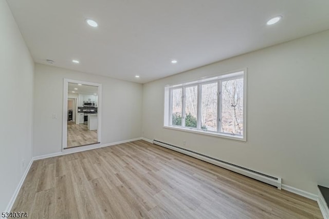 spare room featuring light wood-style floors, recessed lighting, baseboards, and baseboard heating