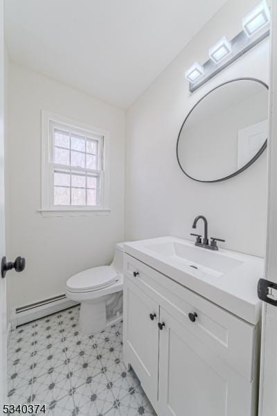 half bathroom with a baseboard radiator, vanity, toilet, and tile patterned floors