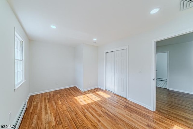 unfurnished bedroom with recessed lighting, visible vents, light wood-style floors, baseboard heating, and a closet