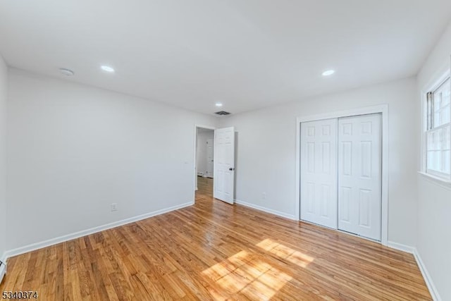 unfurnished bedroom with baseboards, a closet, visible vents, and light wood-style floors