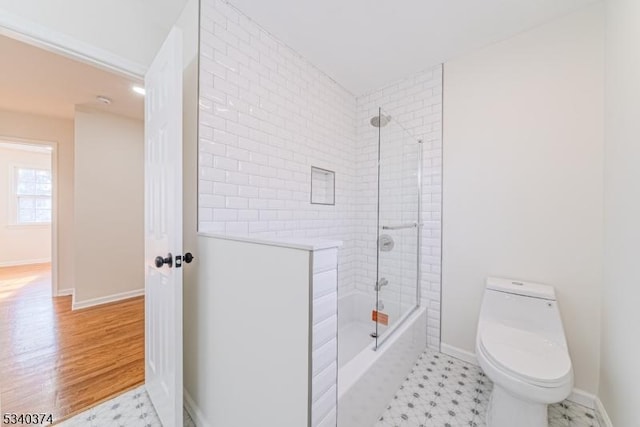 full bath with wood finished floors, shower / tub combination, toilet, and baseboards