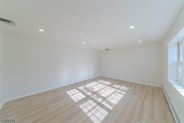 empty room featuring a baseboard heating unit, light wood-type flooring, baseboards, and recessed lighting