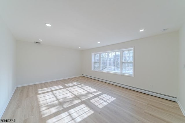 empty room with light wood-style floors, baseboard heating, and recessed lighting